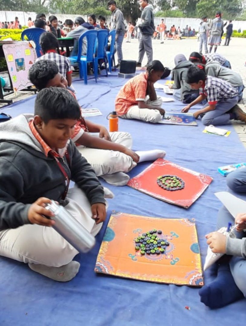 Children working on floor mats outdoors with materials spread around them